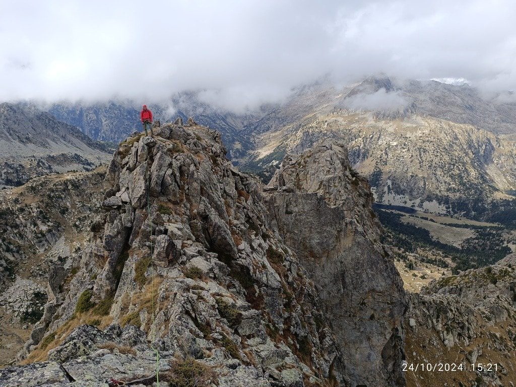 escalador en la cima tras recorrer una cresta en la aguja de la montanyeta