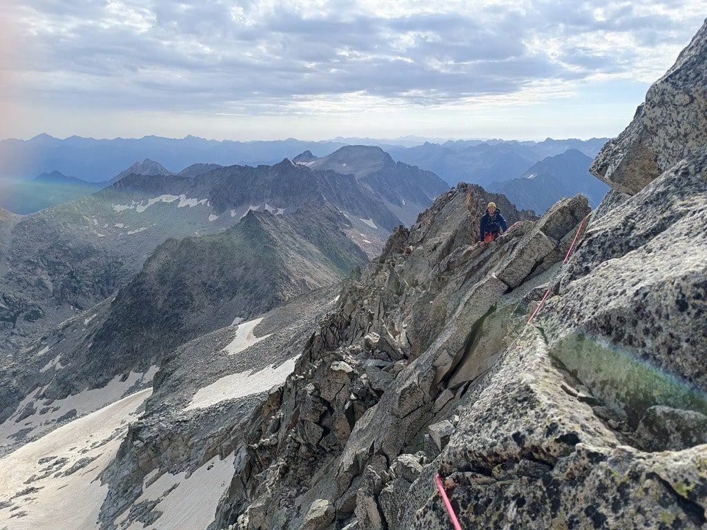 Un escalador en la ascensión con guia en una cresta en pirineos