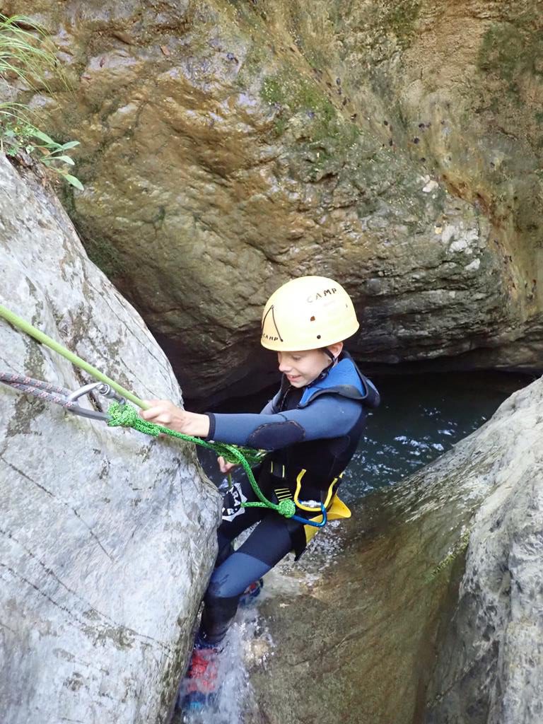 Niño haciendo un rapel en un barranco