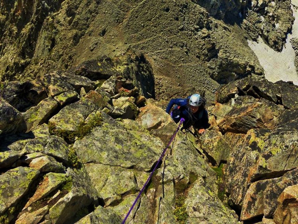 Una escaladora escalando una cresta en el pirineo con un guía de alta montaña.
